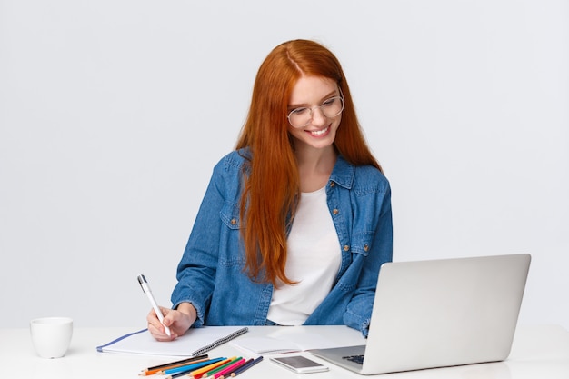 donna di redhead in vetri che legge qualcosa dal computer portatile