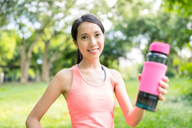 Donna di sport che tiene la bottiglia d'acqua nel parco