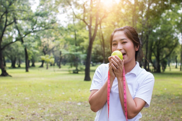 Donna di sport che tiene mela verde e misurazione