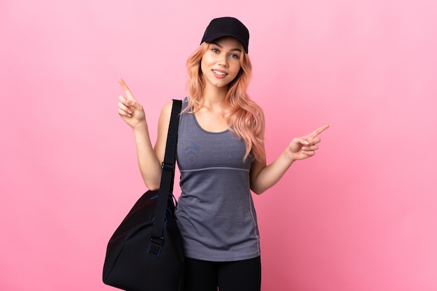 Donna di sport dell'adolescente con la borsa di sport sopra il dito puntato isolato ai laterali e felice
