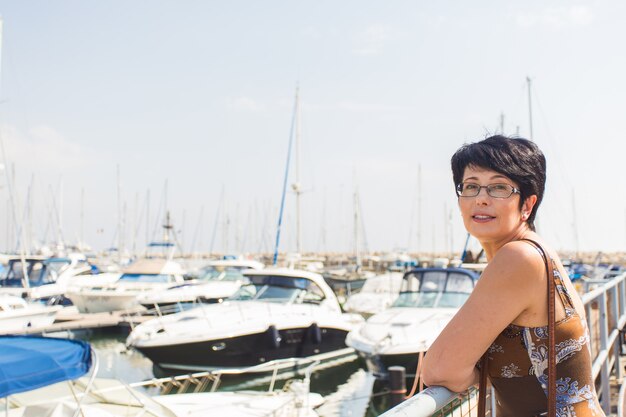Donna di svago in vacanza vicino alla stazione turistica del porticciolo delle barche a vela e dell'yacht.