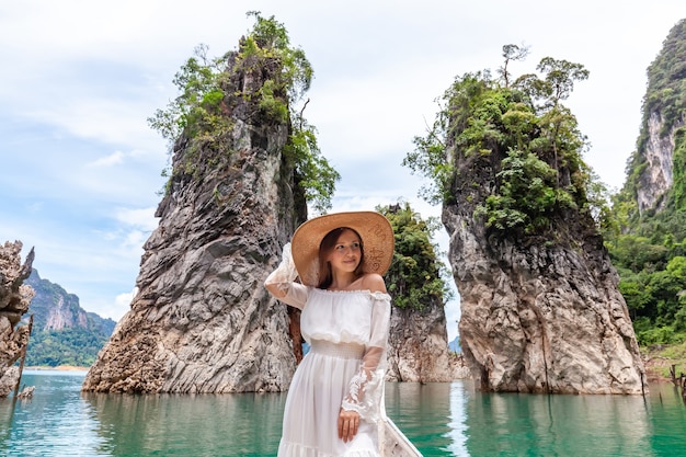 Donna di viaggio che si siede sulla barca vicino alle tre rocce famose nel parco tailandia di khao sok