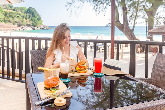 Donna di viaggio con hamburger di fast food caffè e succhi di frutta al caffè all'aperto