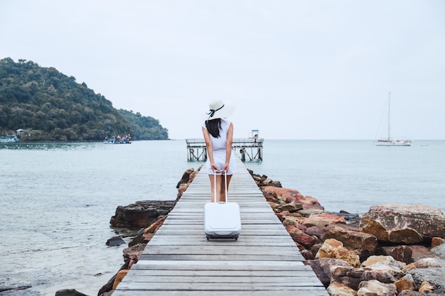 Donna di viaggio con la valigia sulla spiaggia