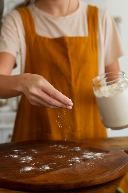 Donna di vista frontale che cucina pizza in cucina