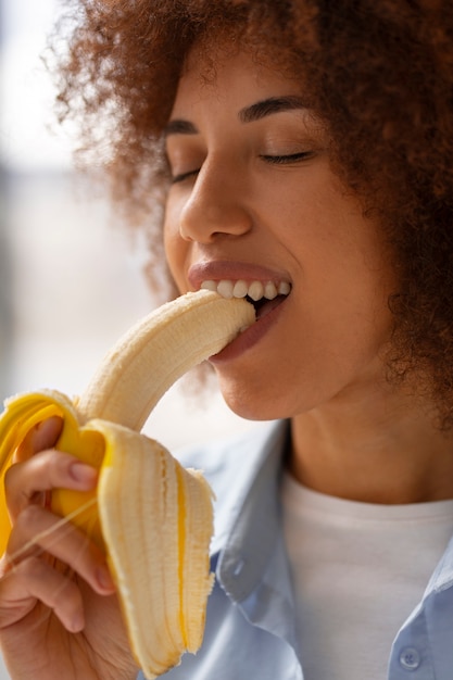 Donna di vista laterale che mangia banana