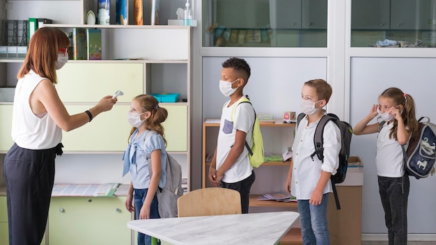 Donna di vista laterale che misura la temperatura dei bambini