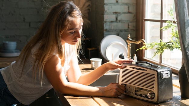 Donna di vista laterale che usando una vecchia radio