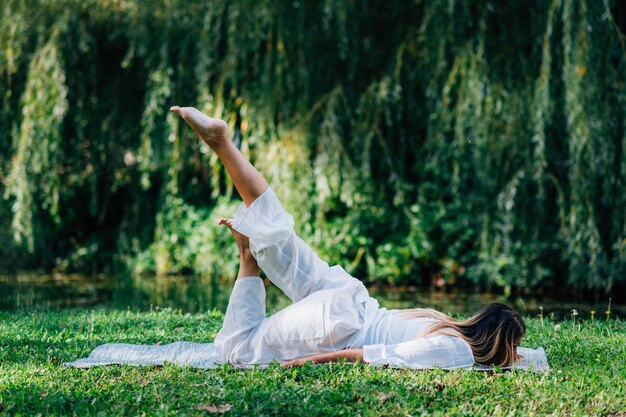 Donna di yoga che fa yoga in riva al lago