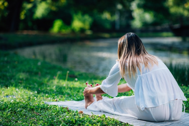 Donna di yoga che fa yoga in riva al lago