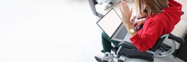 Donna disabile in sedia a rotelle che saluta lo schermo del laptop