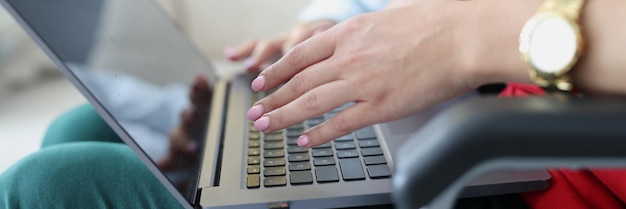 Donna disabile in sedia a rotelle che scrive sul primo piano della tastiera del computer portatile