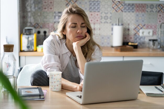 Donna dispiaciuta di mezza età cerca un nuovo lavoro disoccupato durante la quarantena covid sul laptop