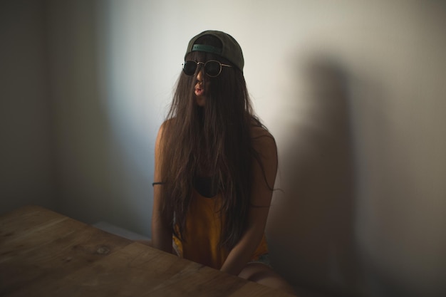 Donna divertente con i capelli che coprono la faccia e le labbra piegate mentre è seduta al tavolo.