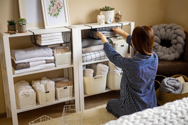 Donna domestica in pigiama che mette ordinatamente la biancheria piegata nell'armadio verticale Marie Kondo