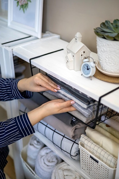 Donna domestica in pigiama che mette ordinatamente la biancheria piegata nell'armadio verticale Marie Kondo