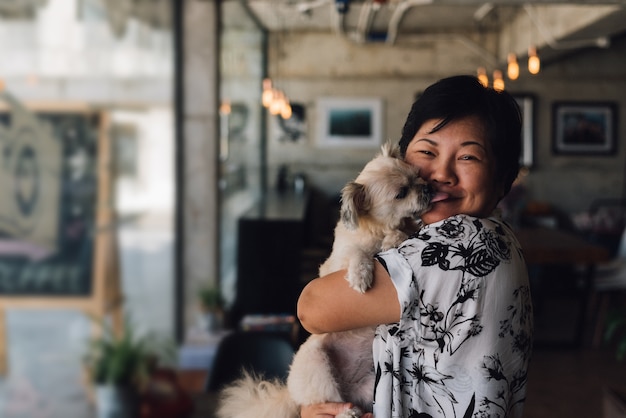Donna e cane asiatici nel caffè della caffetteria