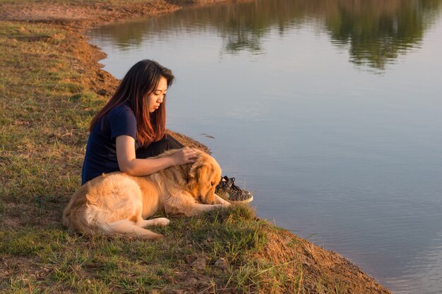 Donna e cane dorato sulla riva del fiume