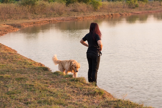 Donna e cane dorato sulla riva del fiume