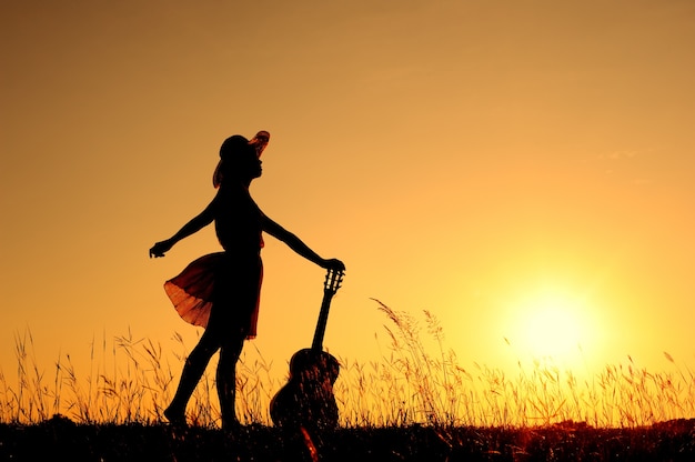 Donna e chitarra con silhouette tramonto