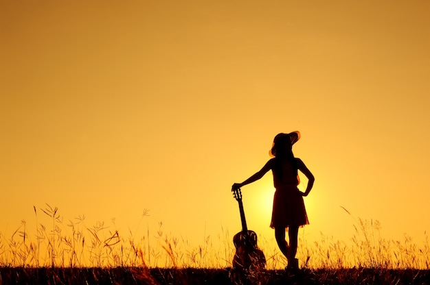 Donna e chitarra con silhouette tramonto