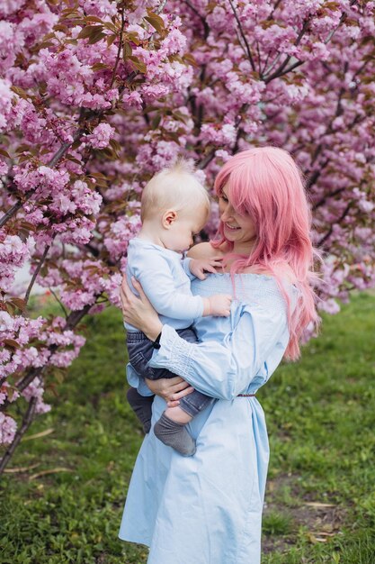 Donna e figlio piccolo nella natura che giocano al parco primaverile Il bambino e la madre si divertono durante le attività del fine settimana nei giardini fioriti di Sakura