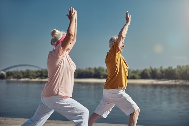 donna e il suo compagno di yoga in piedi in una posa guerriera