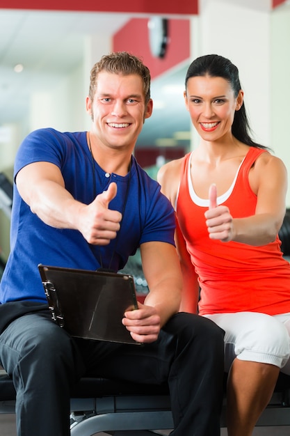 donna e personal trainer in palestra con manubri