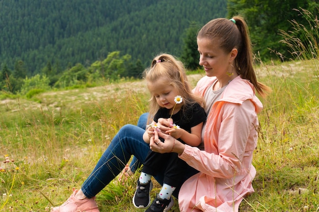 Donna e ragazza seduta sulla collina in montagna. Famiglia che si diverte in vacanza