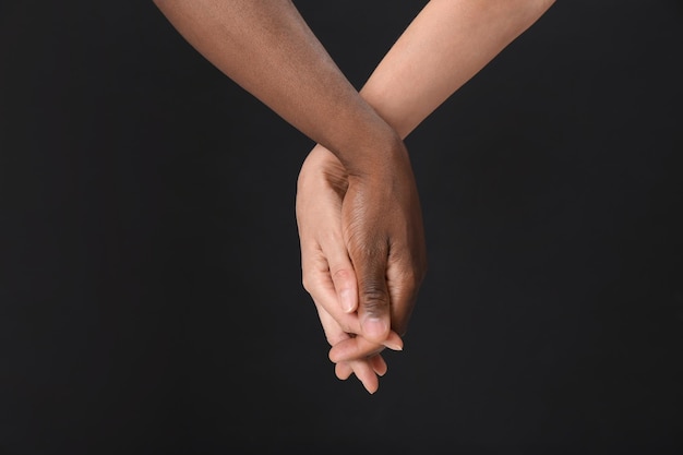 Donna e uomo afroamericano che si tengono per mano su sfondo nero primo piano