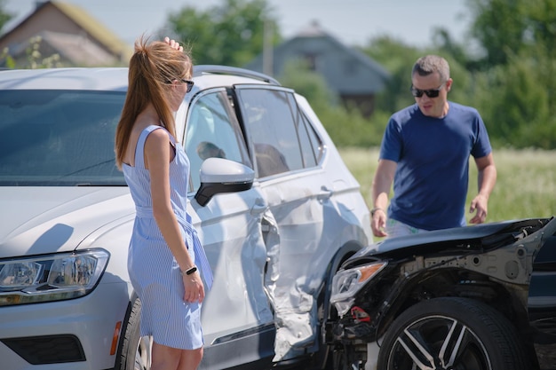 Donna e uomo arrabbiati conducenti di veicoli gravemente danneggiati che sostengono chi è colpevole di un incidente stradale sul lato della strada Sicurezza stradale e concetto assicurativo