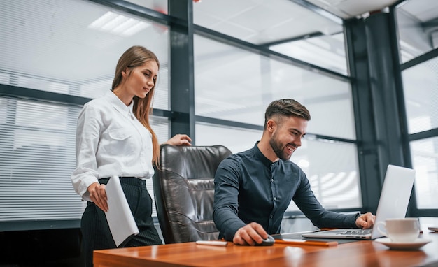 Donna e uomo in abiti formali che lavorano insieme al chiuso in ufficio al tavolo.