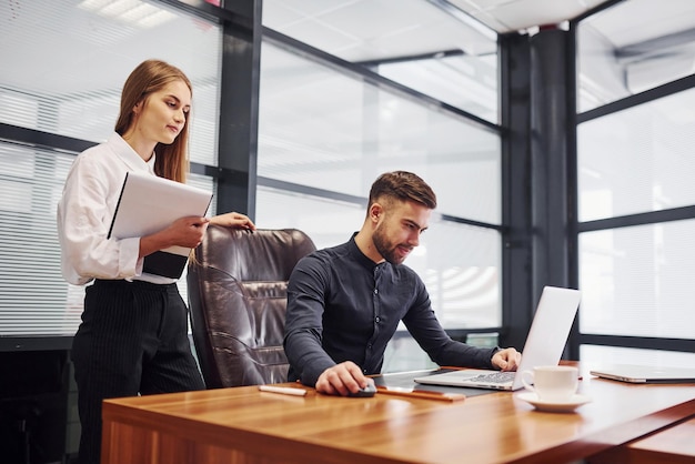 Donna e uomo in abiti formali che lavorano insieme al chiuso in ufficio al tavolo.