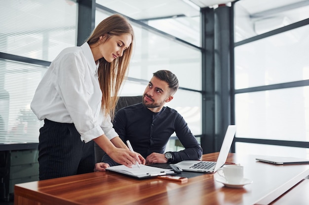 Donna e uomo in abiti formali che lavorano insieme al chiuso in ufficio al tavolo.