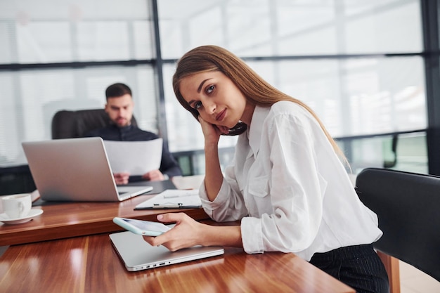 Donna e uomo in abiti formali che lavorano insieme al chiuso in ufficio vicino a un tavolo con documenti.