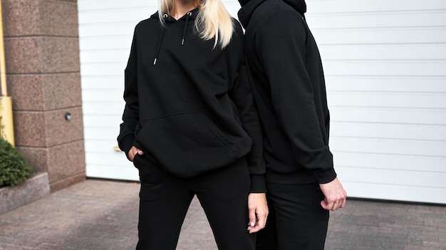 Donna e uomo indossano una felpa con cappuccio nera senza logo Abbigliamento sportivo di base senza logo Mockup di felpa a maniche lunghe