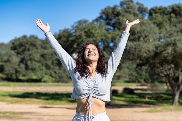 Donna Eccitata Alzando Le Braccia In Un Parco O In Una Foresta. Concetto di libertà