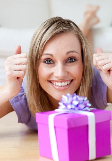 Donna eccitata guardando un regalo sdraiato sul pavimento