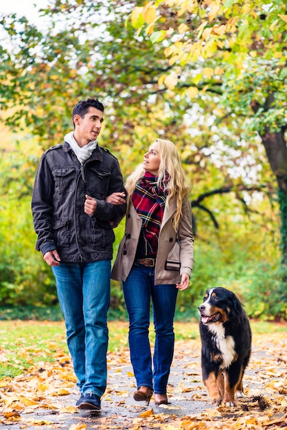 Donna ed uomo con cane che fa passeggiata d&#39;autunno