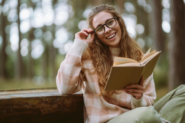 Donna elegante che legge un libro nel parco d'autunno