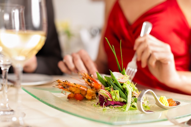 Donna elegante che mangia e che beve in ottimo ristorante