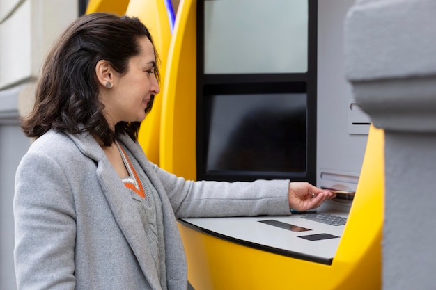 Donna elegante che preleva contanti a un bancomat. Spazio per il testo.