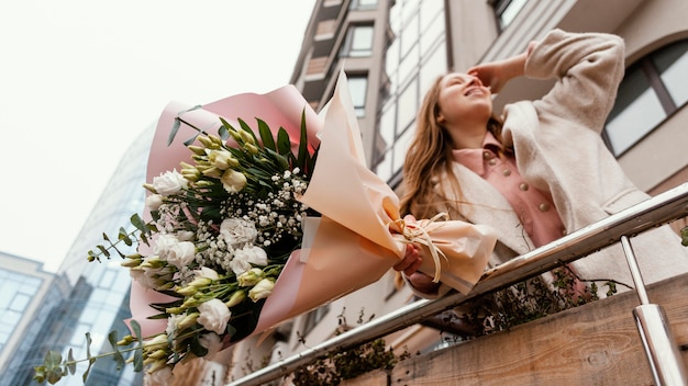 Donna elegante che tiene il mazzo di fiori all'aperto