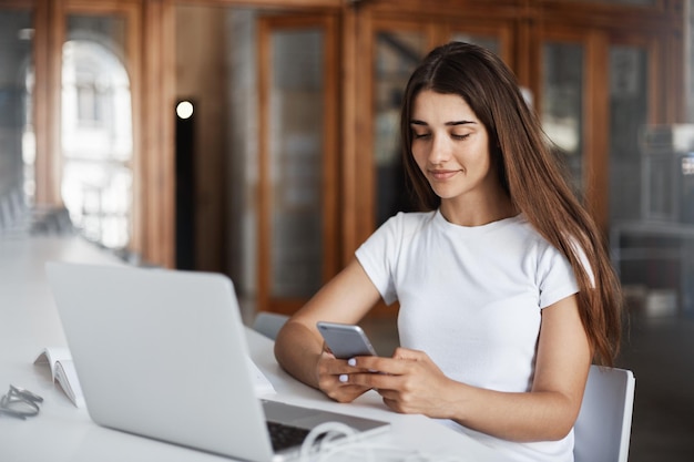 Donna elegante che usa lo smartphone per inviare messaggi agli amici e invitarli a una festa di notte Sorridere e pubblicare sui social media Concetto di comunicazione