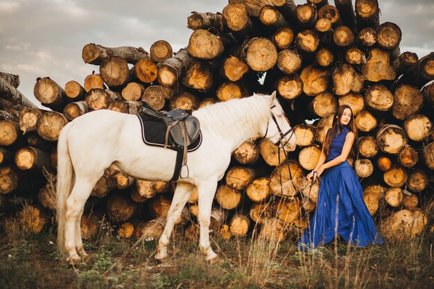 Donna elegante con cavallo bianco ai tronchi.