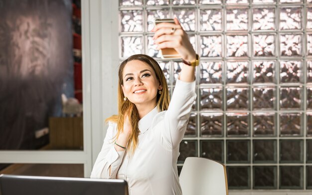 Donna elegante di affari che fa selfie con il cellulare.