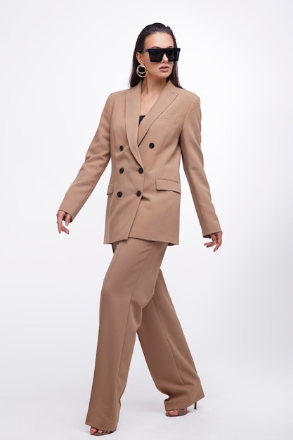 donna elegante in abito abbastanza marrone e beige, giacca, pantaloni su sfondo bianco