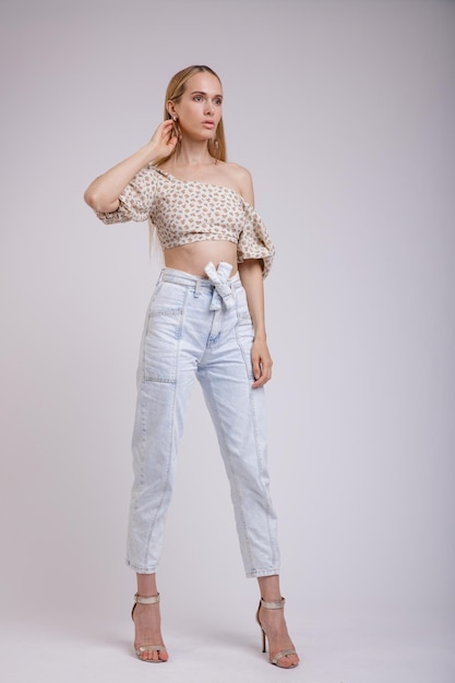 donna elegante in graziosi jeans denim blu, beige con motivo floreale in alto su sfondo bianco