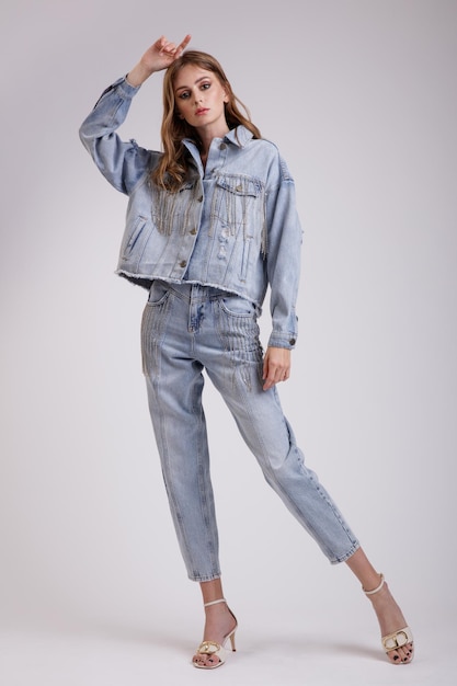 Donna elegante in una bella giacca oversize di jeans in denim con pantaloni di strass su sfondo bianco