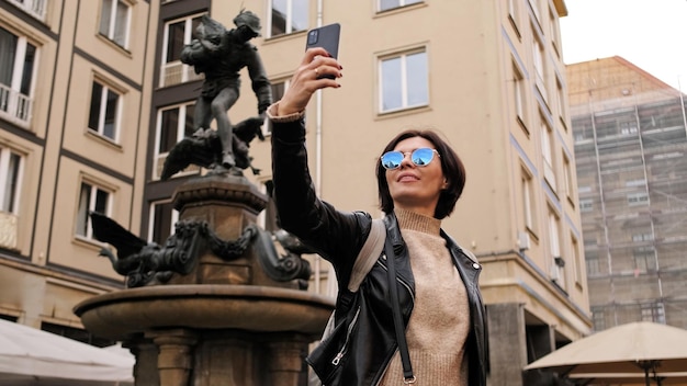 Donna elegante passeggiando per le strade storiche turistiche di Dresda catturando immagini di monumenti